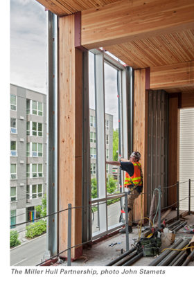 Builder alongside Redwood glum beams inside a building