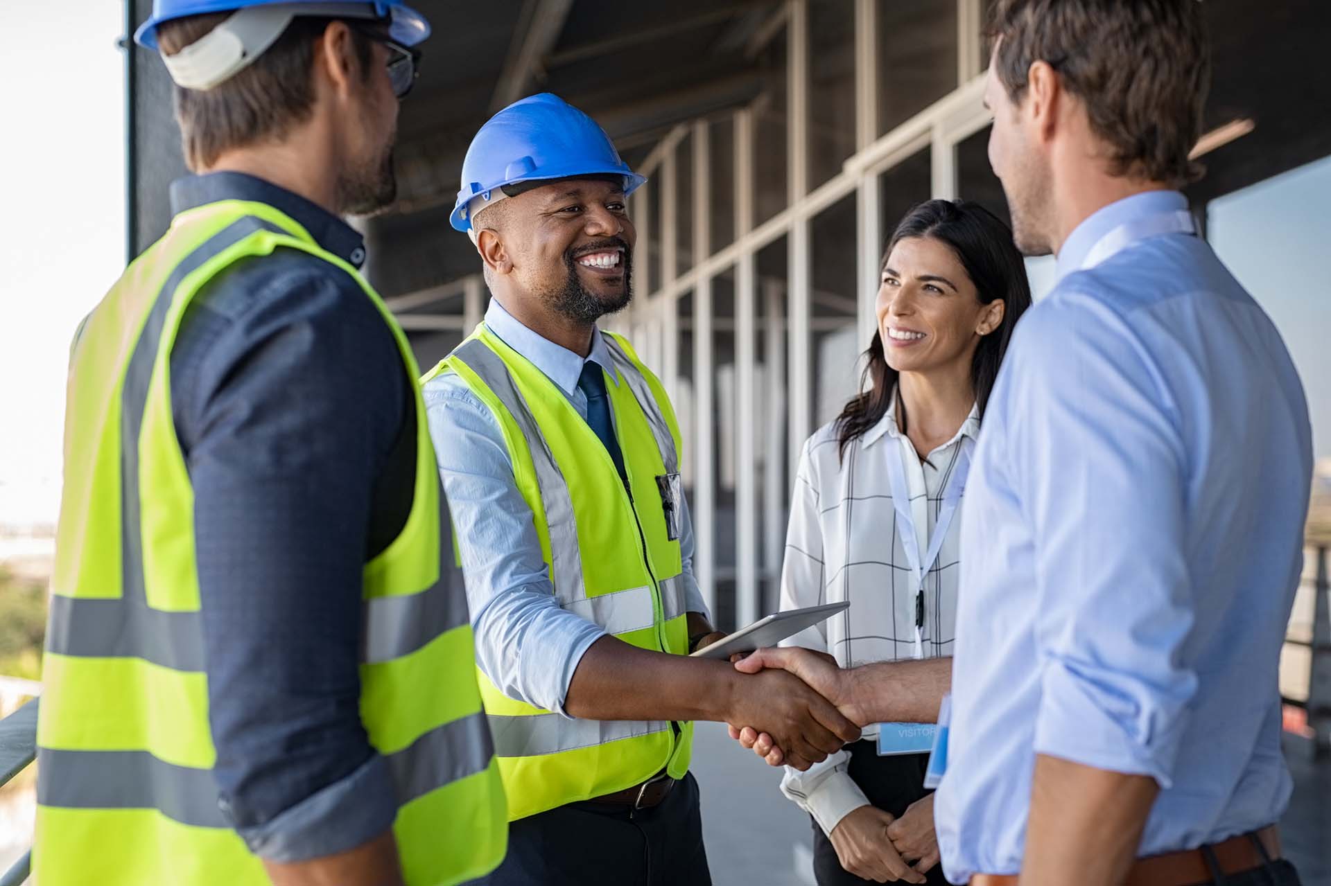 Smiling engineer shaking hands at construction site with architect.